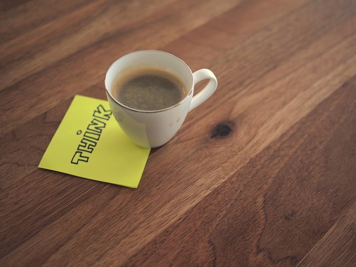 Tasse de café sur un post-it "Think" illustrant la réflexion lors de l'élaboration d'un cahier des charges pour un projet de site web.